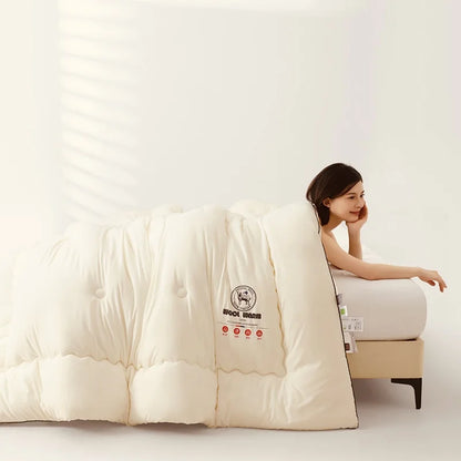 Woman sitting on a bed with a large white comforter, featuring a brand label.